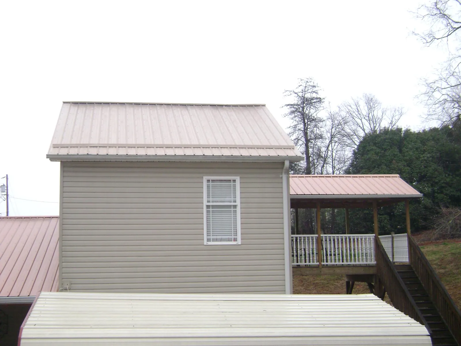 Tan metal roofs on a two story addition and attached porch, from a Roof Replacement job in Elizabeth